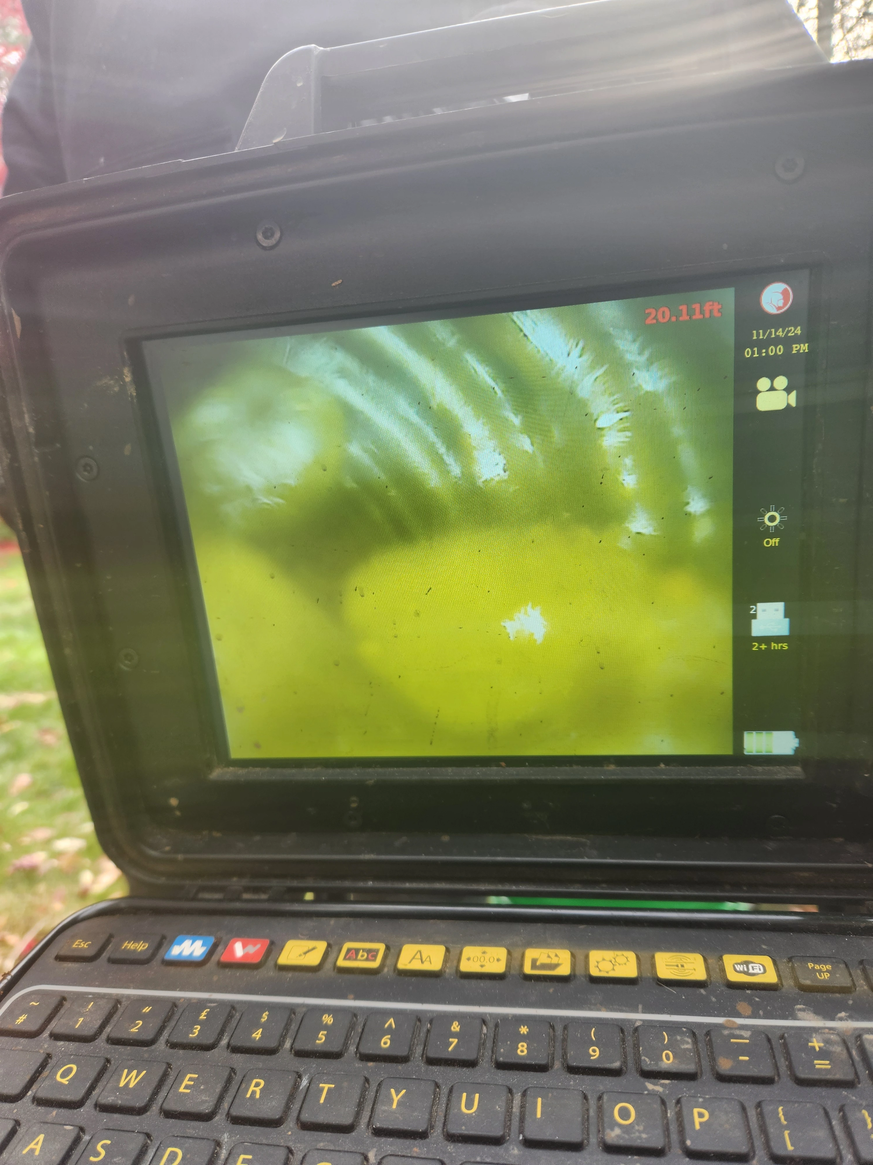 Sewer inspection camera screen showing interior of a pipe with buildup.