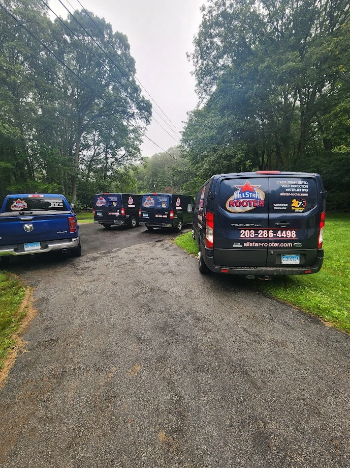 Multiple plumbing service vans parked along a residential road.