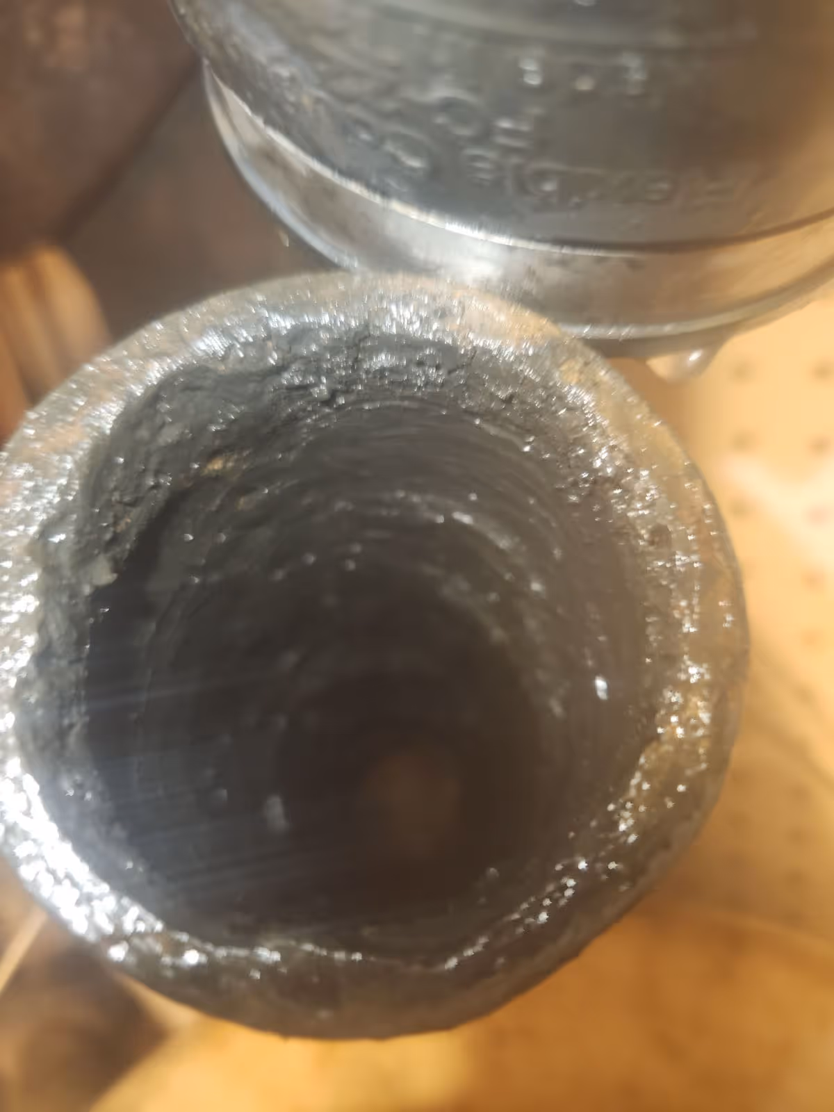 Close-up view inside a metal pipe with significant scale buildup on the inner walls.