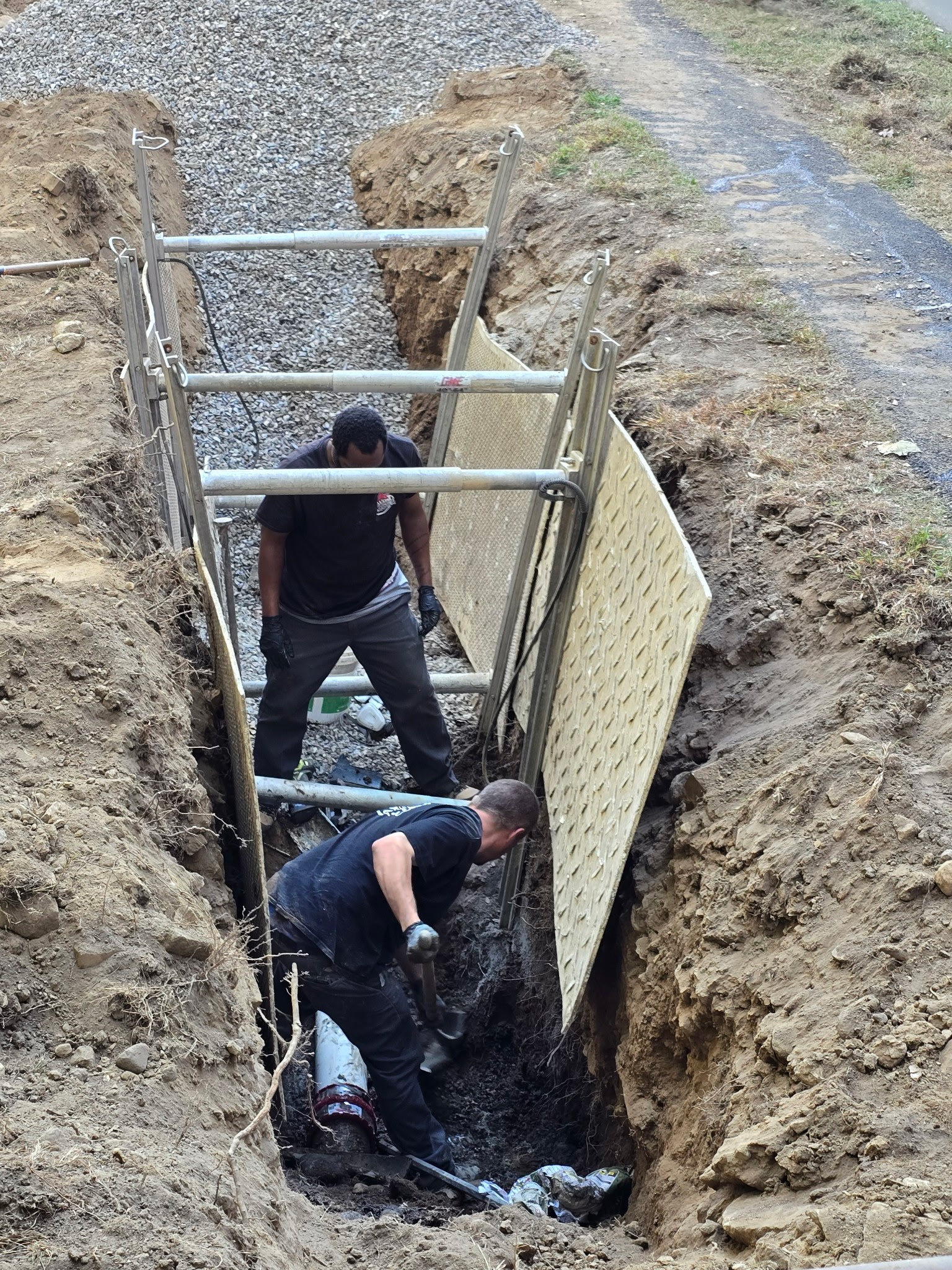 Plumbers installing curtain drain system in trench for drainage solution in Norwalk CT