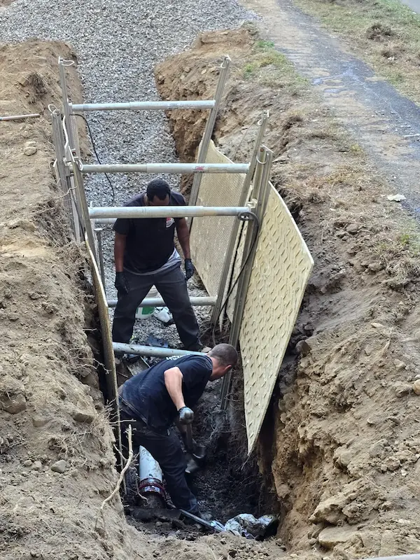 Plumbers installing curtain drain system in trench for drainage solution in Norwalk CT