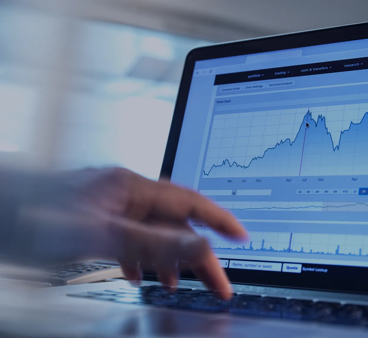 Professional pointing at laptop displaying financial graphs and analytics