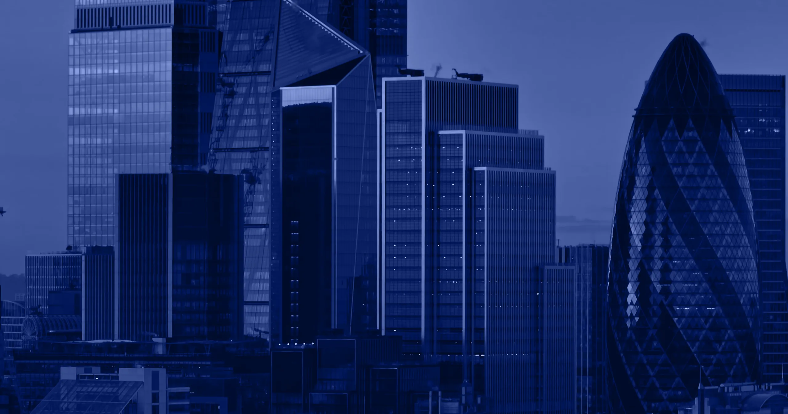 Skyline view of modern glass skyscrapers including the distinctive Gherkin building in London at dusk.