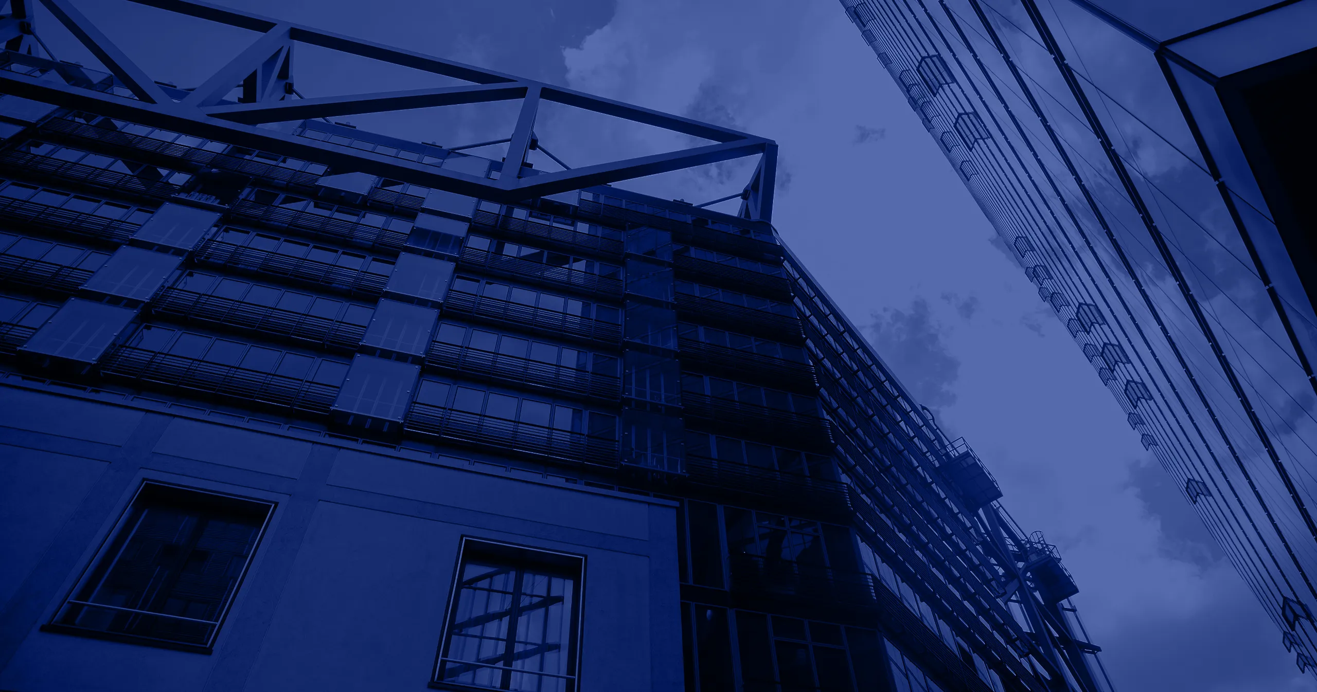 Low-angle view of modern glass and steel skyscrapers against a cloudy sky.