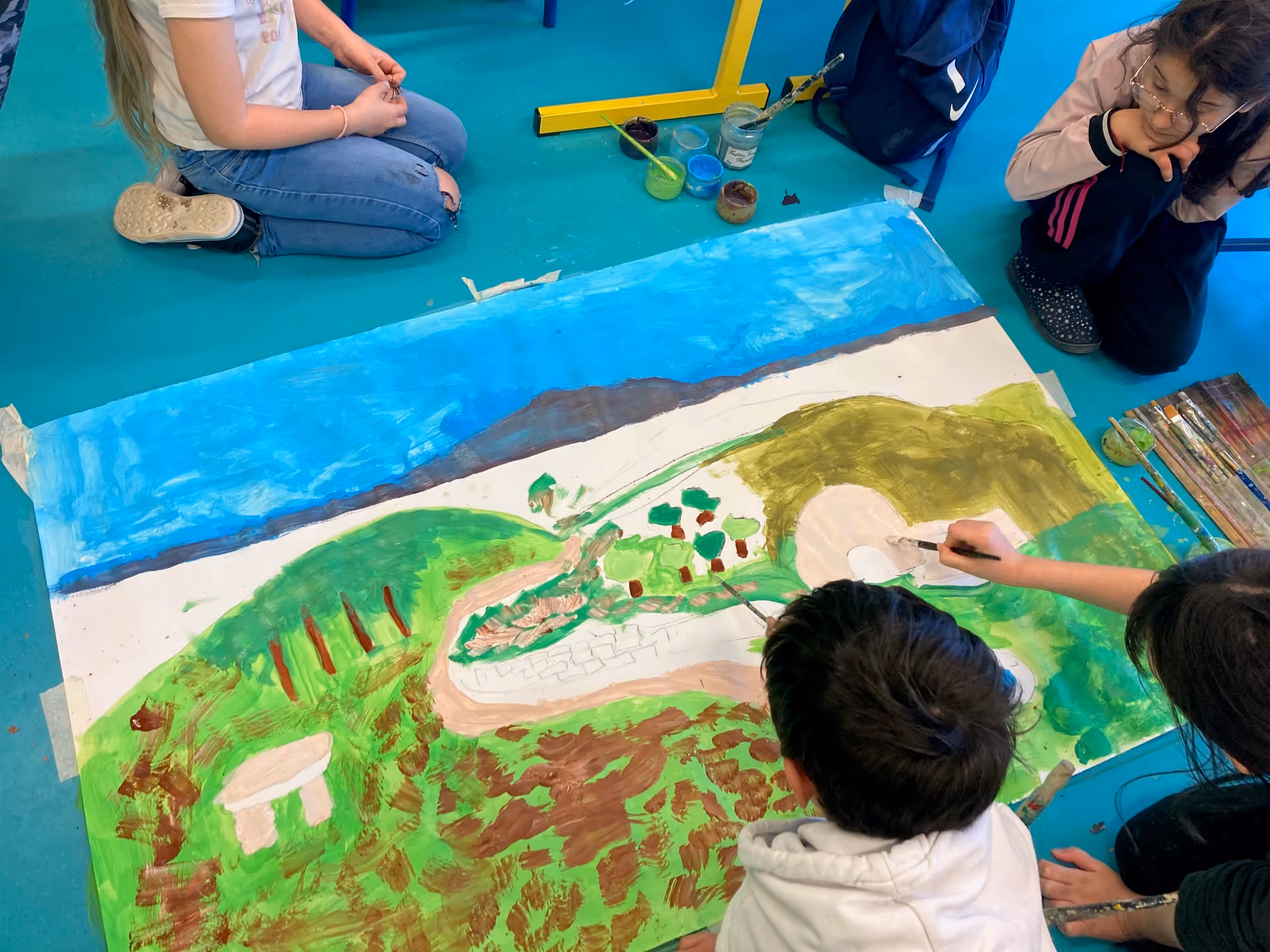 A group of children are painting a picture of a mountain.