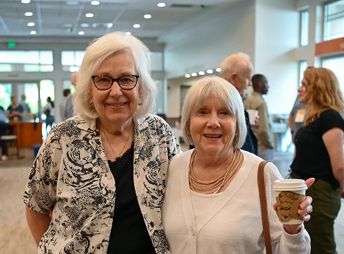 Two smiling senior women standing together in a bright indoor space
