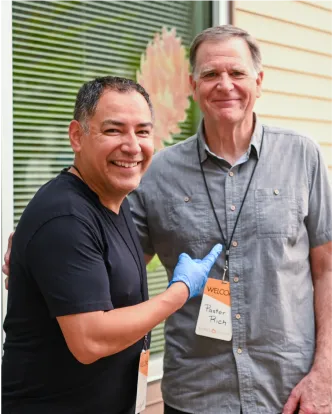 Two smiling colleagues standing together outside, wearing casual shirts