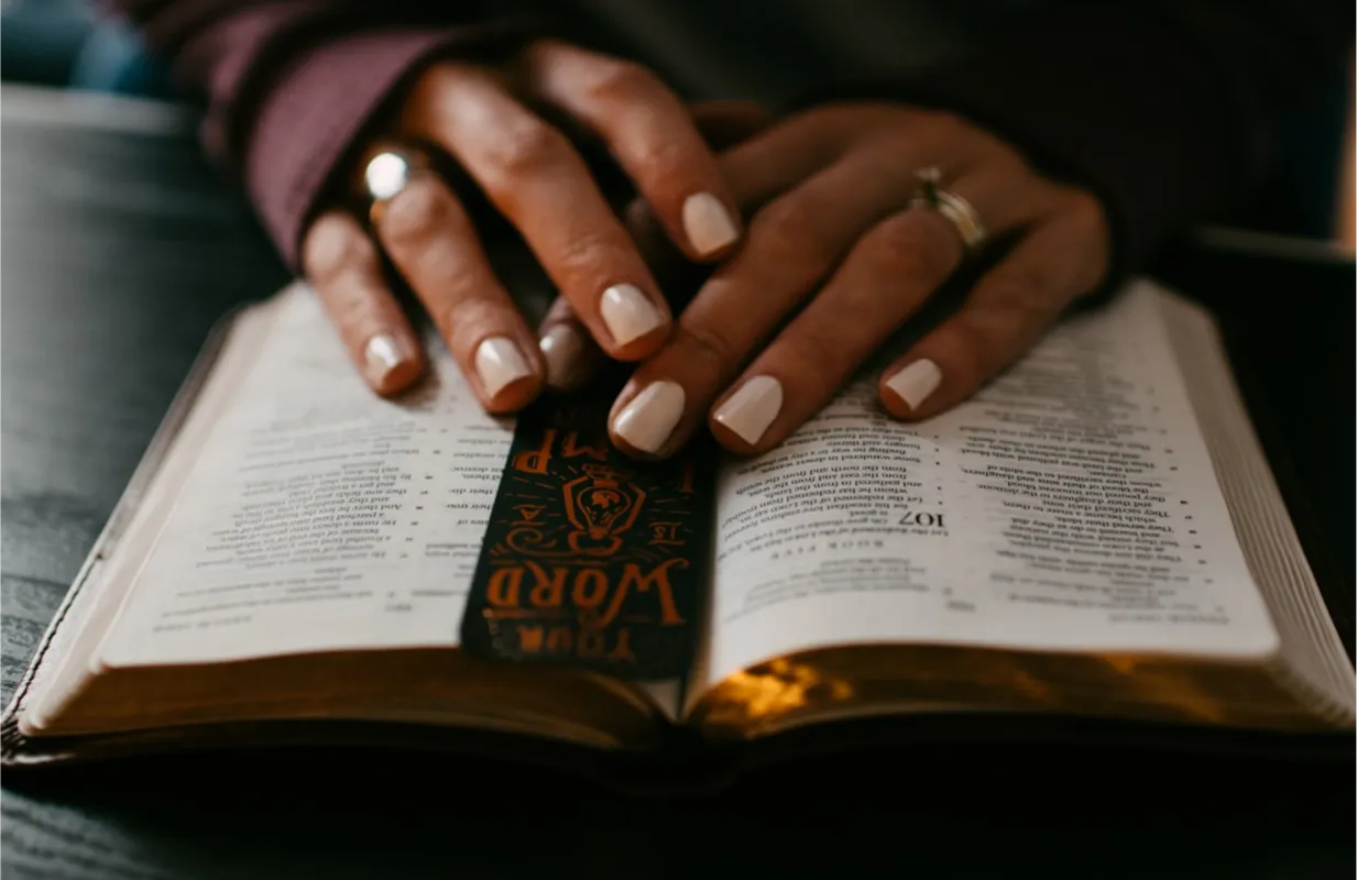 Hands resting on an open book with a decorated bookmark