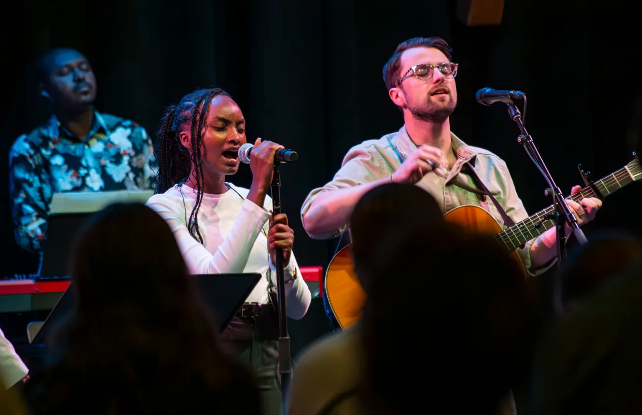 Musicians performing passionately on stage with microphones and guitar