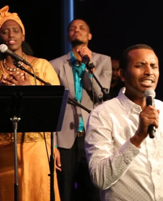 Three passionate singers performing on stage with microphones