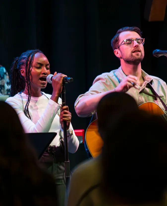 Two musicians performing together on stage, singing and playing guitar