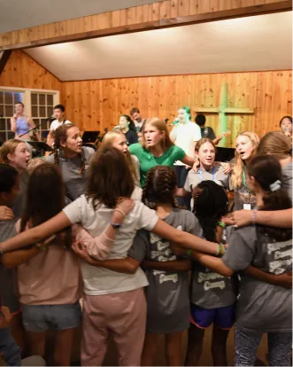Group of people in wooden room linking arms, seeming to interact energetically