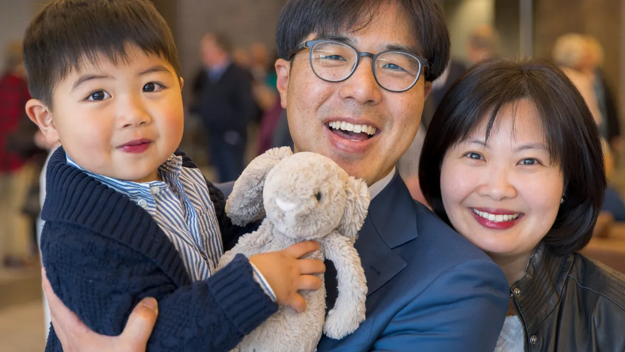 Joyful family with young child and stuffed animal, smiling together