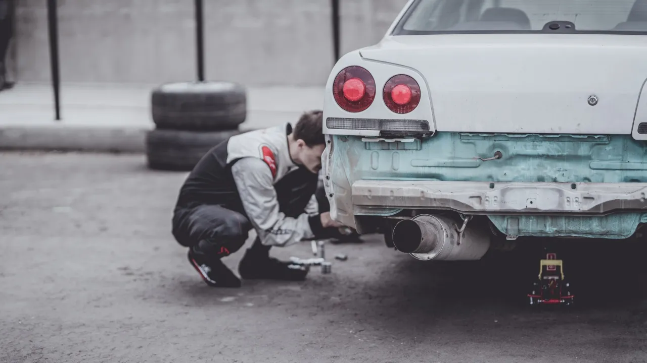 Mechanic working on white sports car with round tail lights