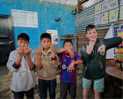 Four children pose in classroom with colorful alphabet wall decorations