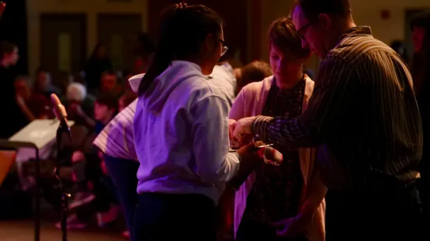 People conversing under purple stage lighting at an event or performance