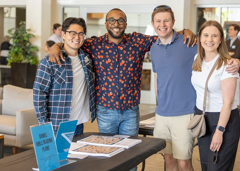 Four coworkers smiling together at an office table with board game
