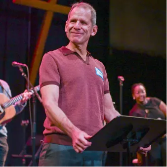 Smiling musician in red shirt performing on stage with band