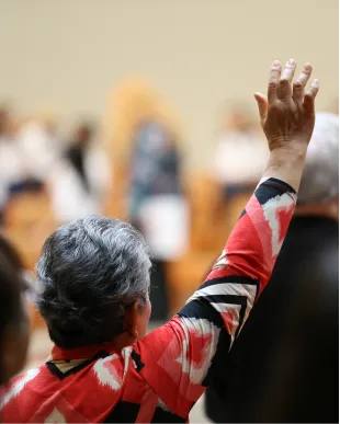 Person in red jacket raising hand at conference or event