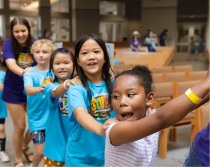 Excited children in matching blue shirts at summer camp or event