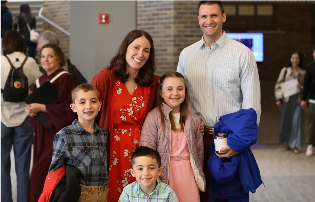 Smiling family of five posing together in a school or community building