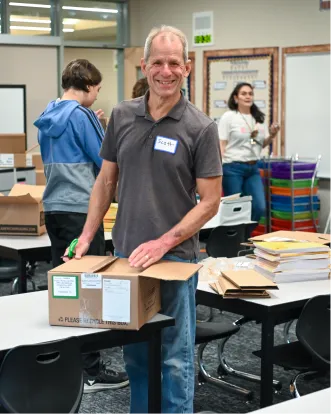 Smiling volunteer sorting packages in a classroom or community center
