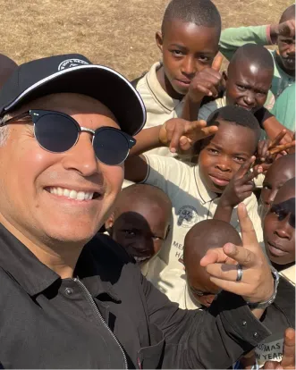 Smiling traveler taking selfie with group of children giving peace signs