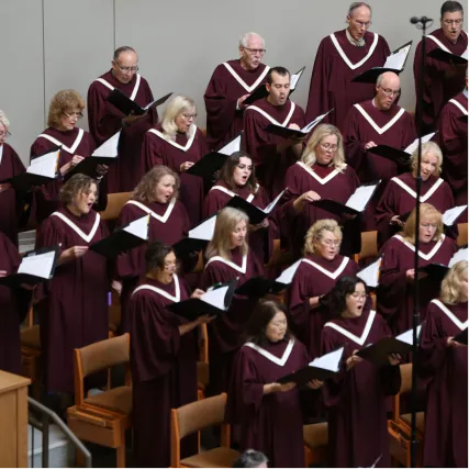 Adult choir in burgundy robes singing together during performance