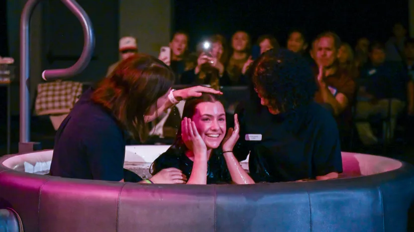 Smiling person sitting in a round booth with people around her