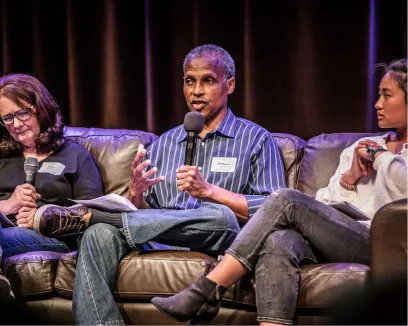 Panel discussion with three speakers seated on a leather couch
