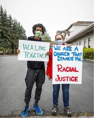 Two protesters with signs advocating for racial justice and healing together