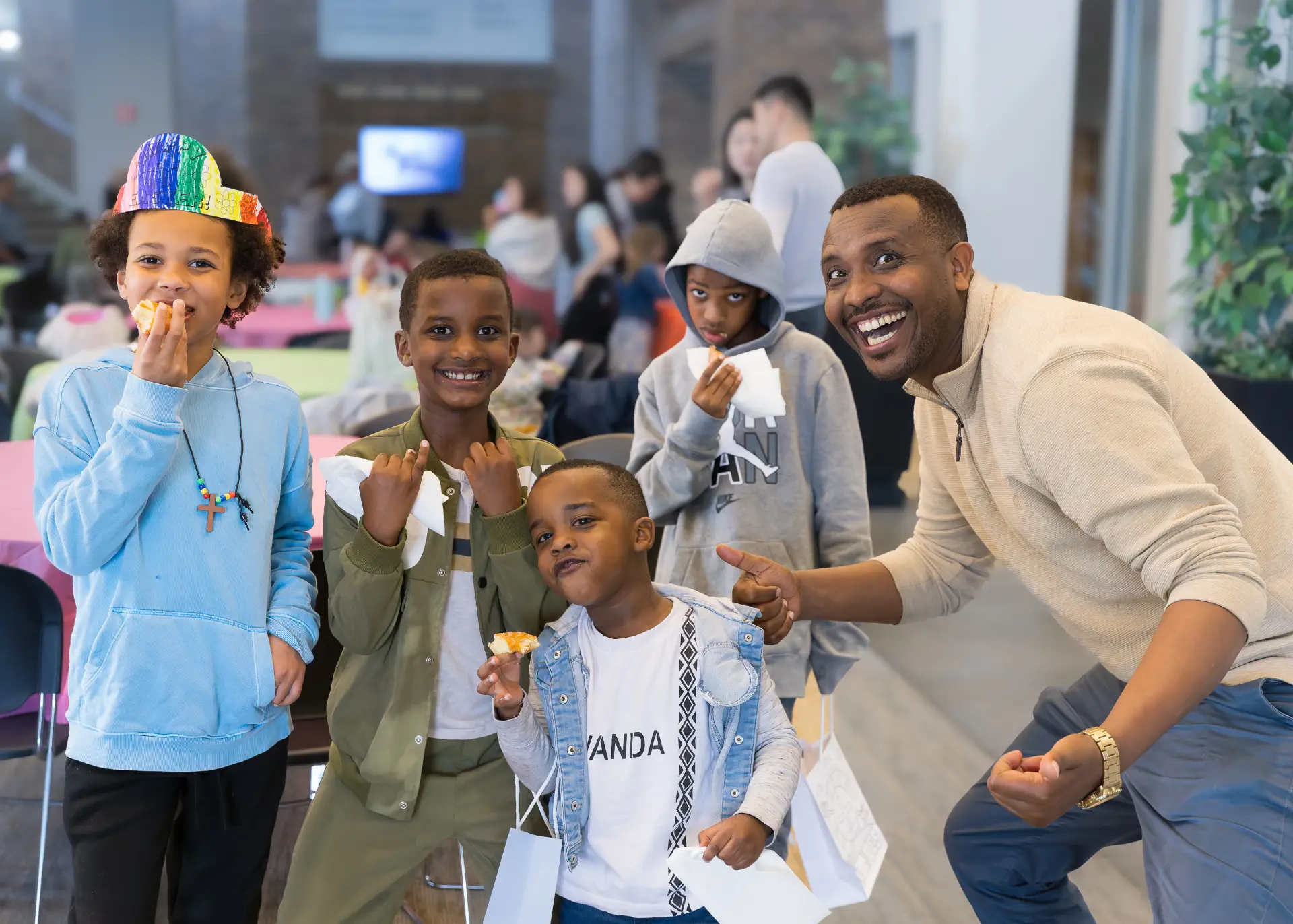 A group of children and an adult smile and pose together while enjoying snacks during a church community event.