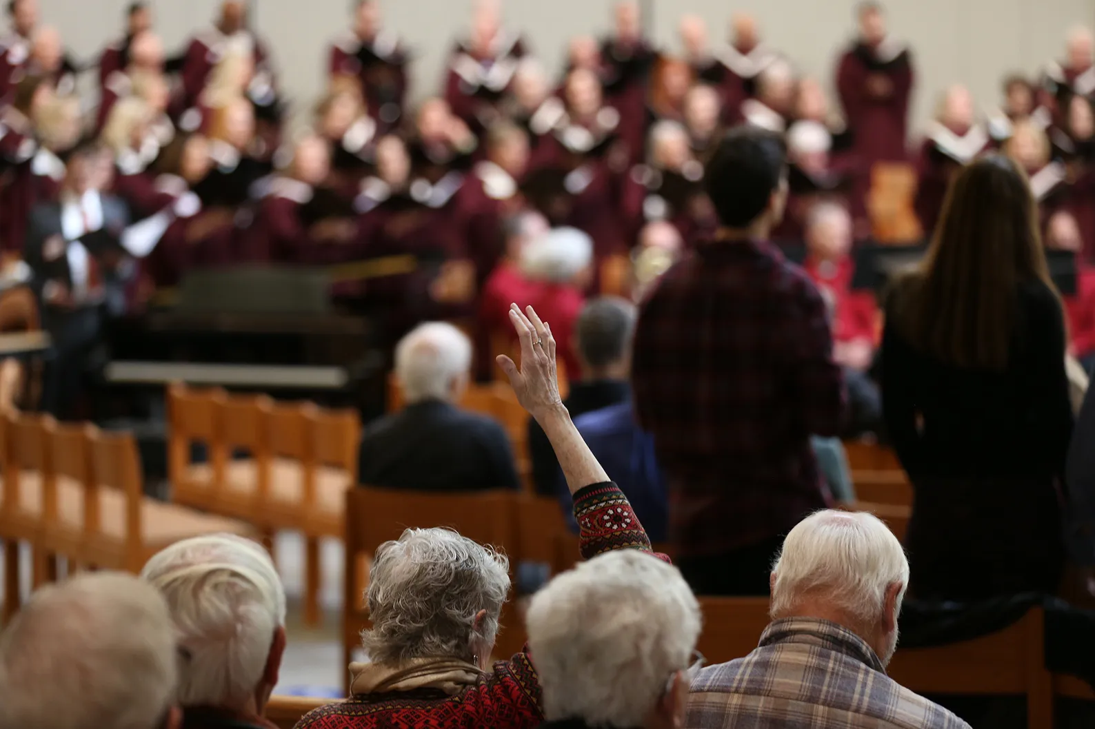 Choir performs on stage while elderly audience members watch attentively