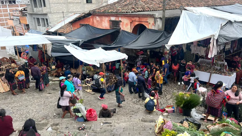 Bustling outdoor market with colorful tents and people selling produce