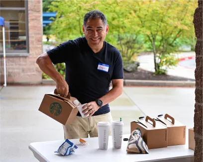 Smiling worker preparing Starbucks coffee boxes on outdoor table