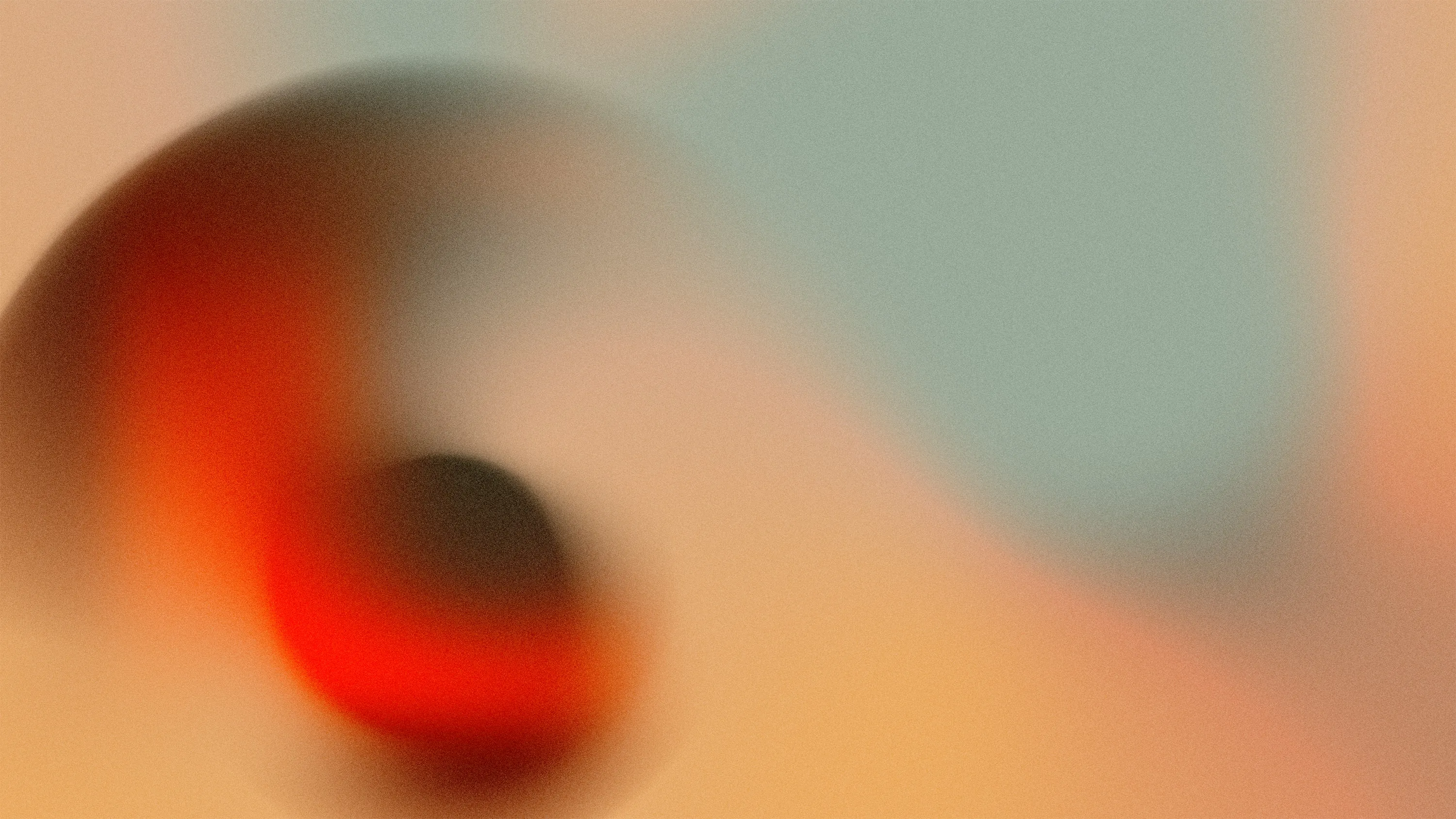 Abstract blurred swirl with a dark center surrounded by gradients of red, beige, and blue.