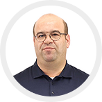 Portrait of a middle-aged man with glasses, short hair, and a dark polo shirt, smiling slightly against a white background.