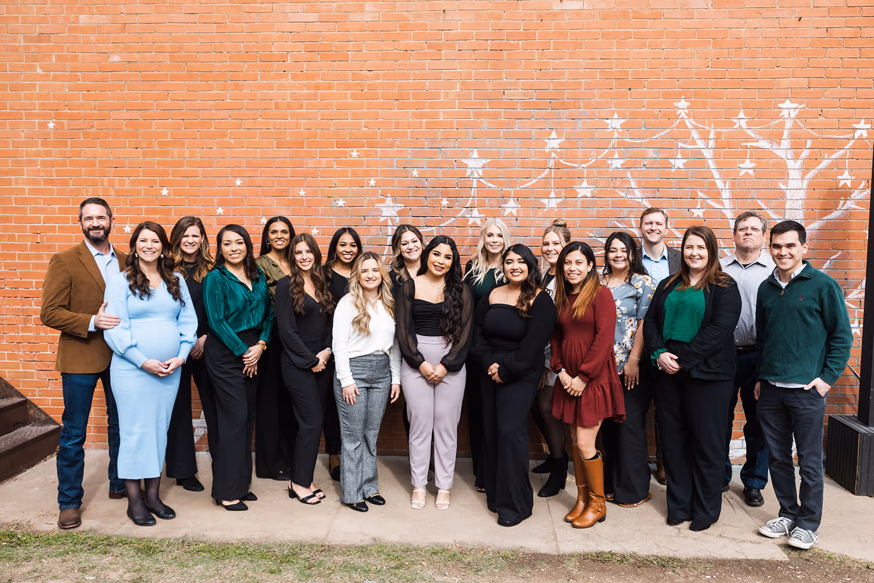 A group of people standing in front of a brick wall.
