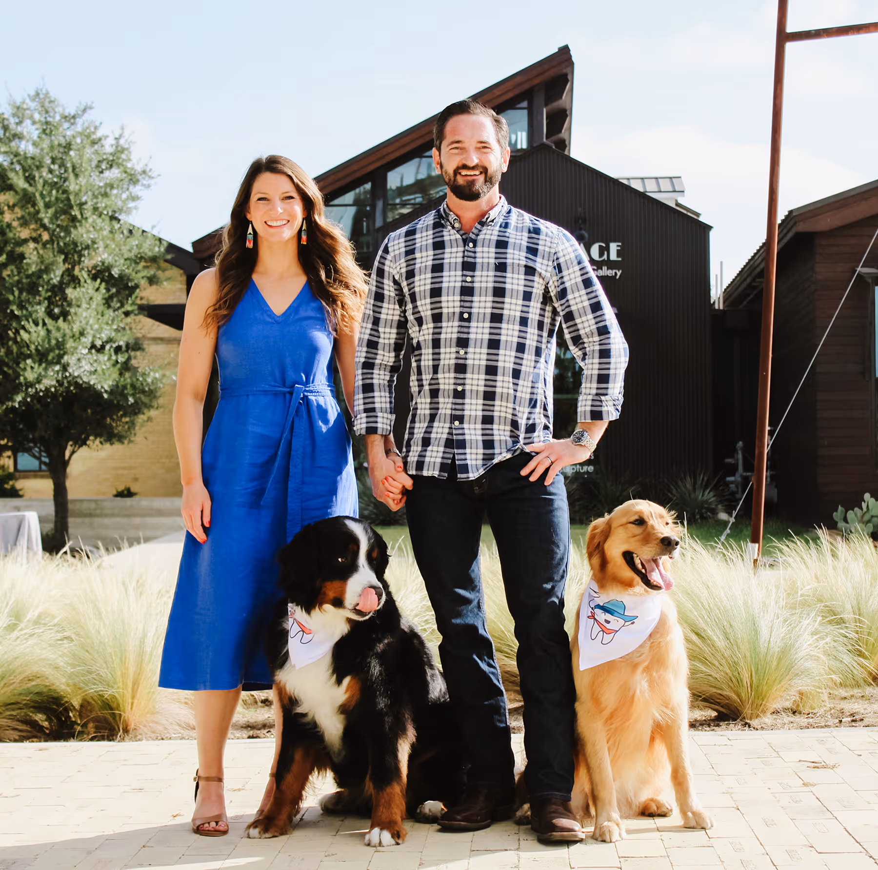 A man and woman standing next to two dogs.