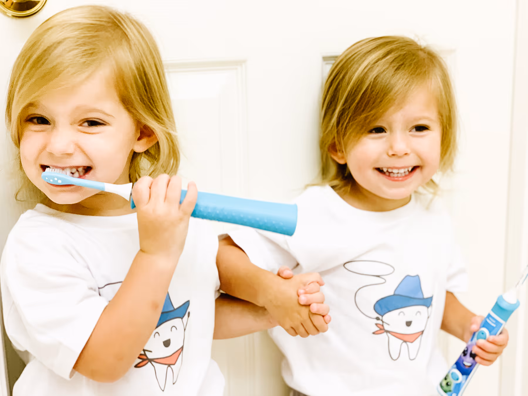 Two little girls brushing their teeth with toothbrushes.