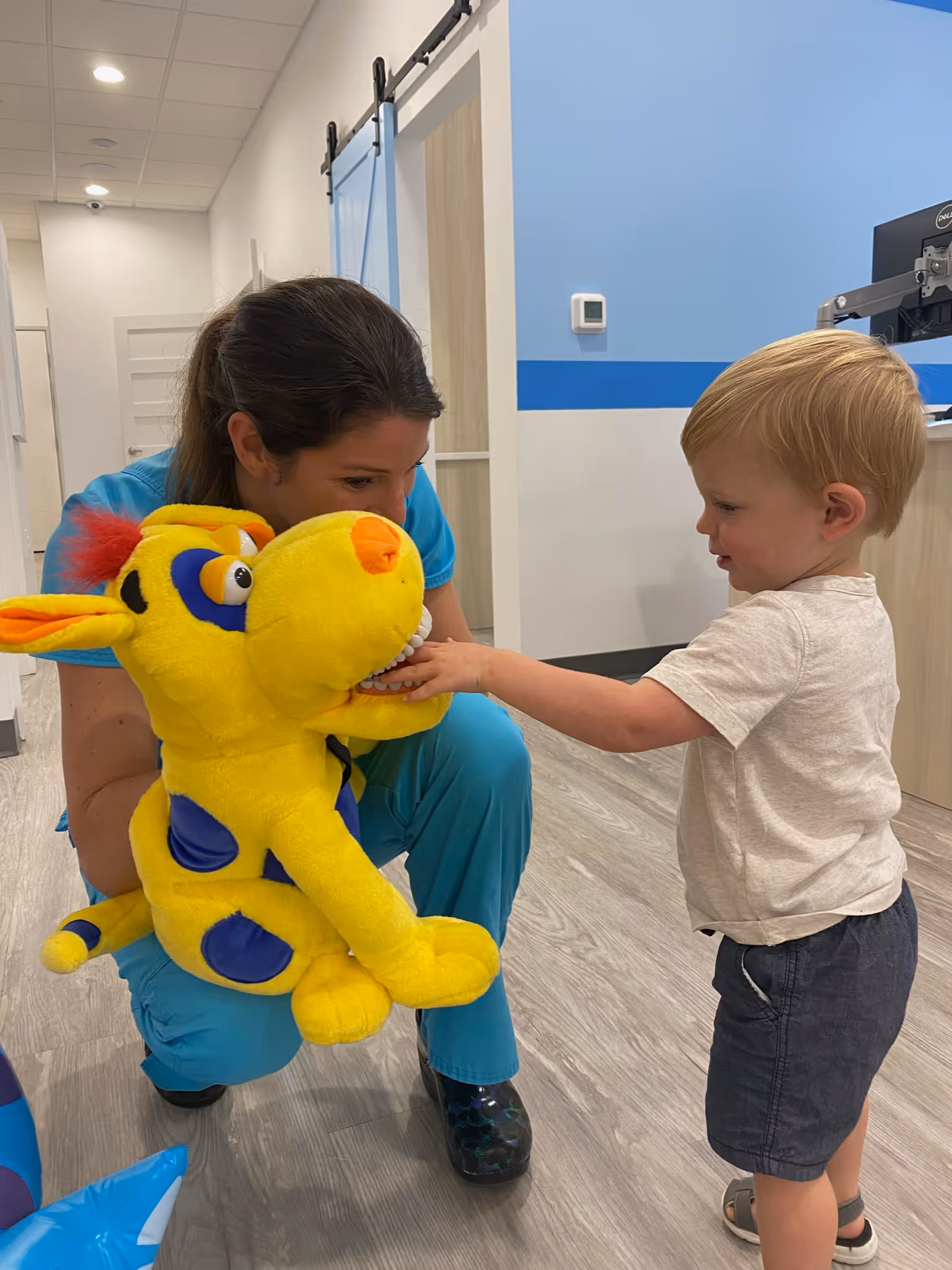 A little boy is playing with a stuffed animal.