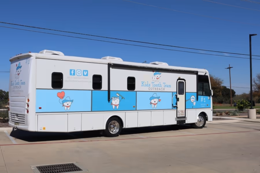 A white and blue bus parked in a parking lot.