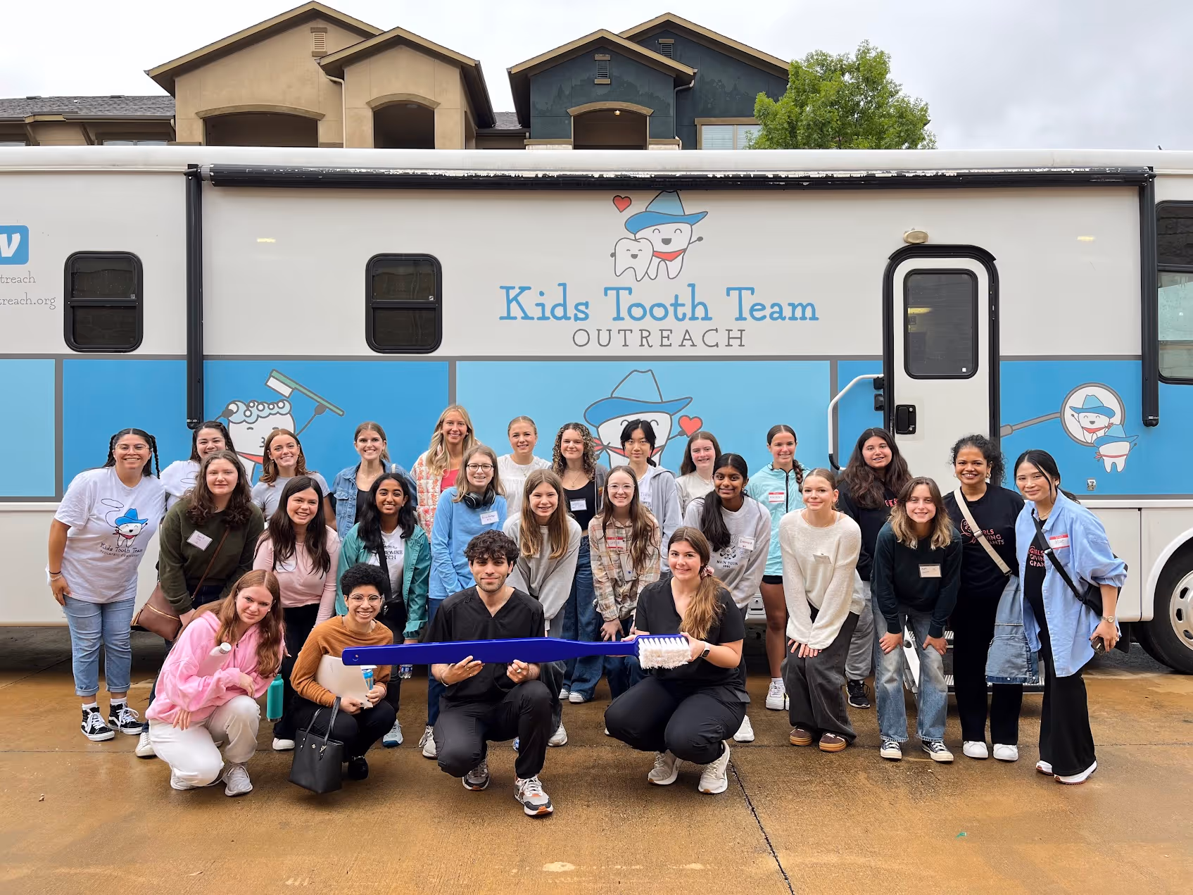 A group of people standing in front of a blue and white trailer.