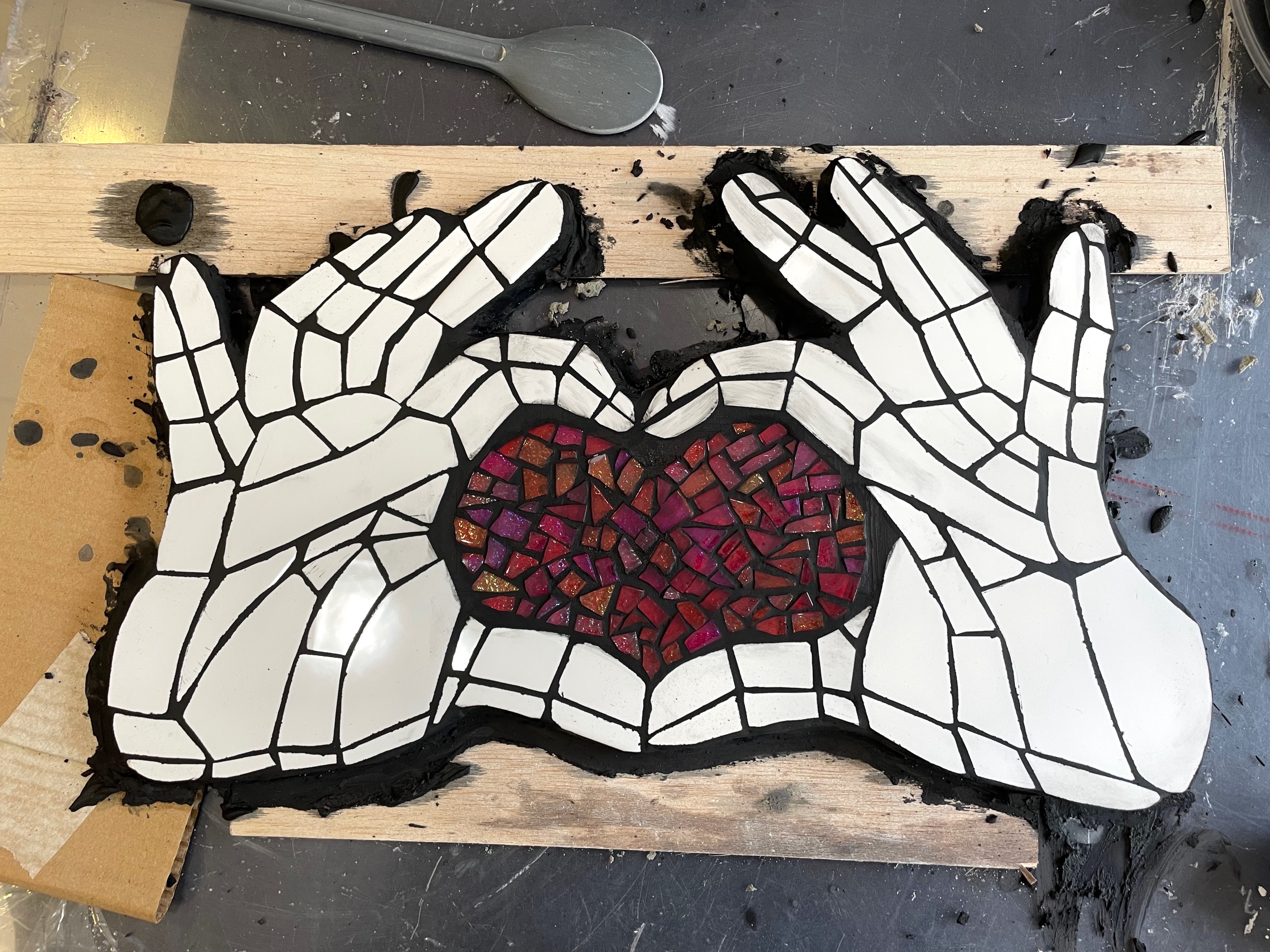 Pormenor de mosaico das mãos na fase de colocação do betume de junt