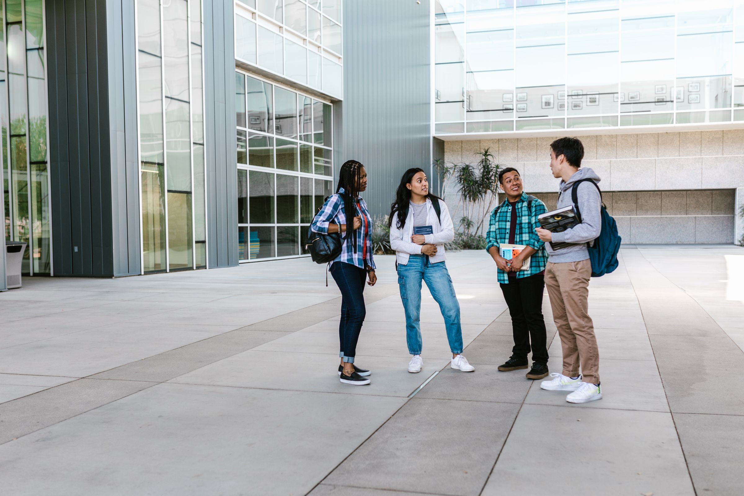 Four students talking together outside a modern campus building