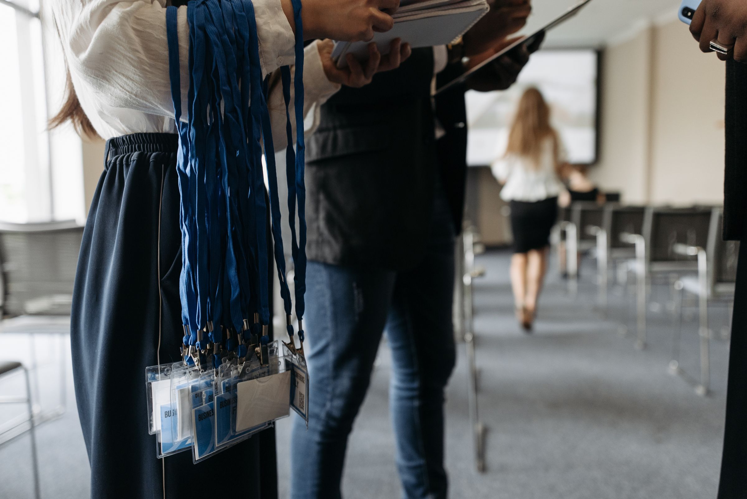Staff holding stacks of lanyards and name badges before an event