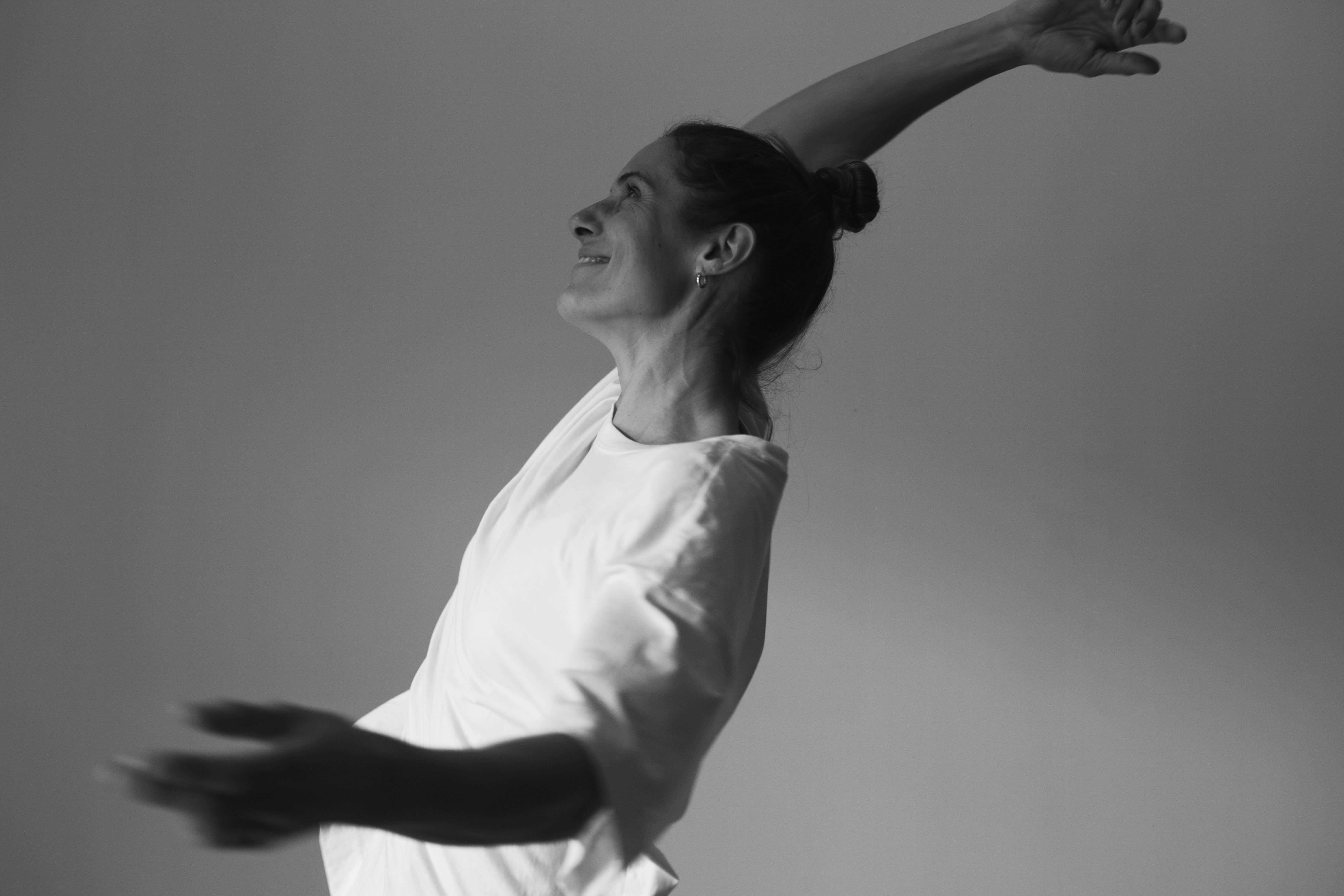 Reni Bickel moving with outstretched arms in a white t-shirt, black-and-white photo