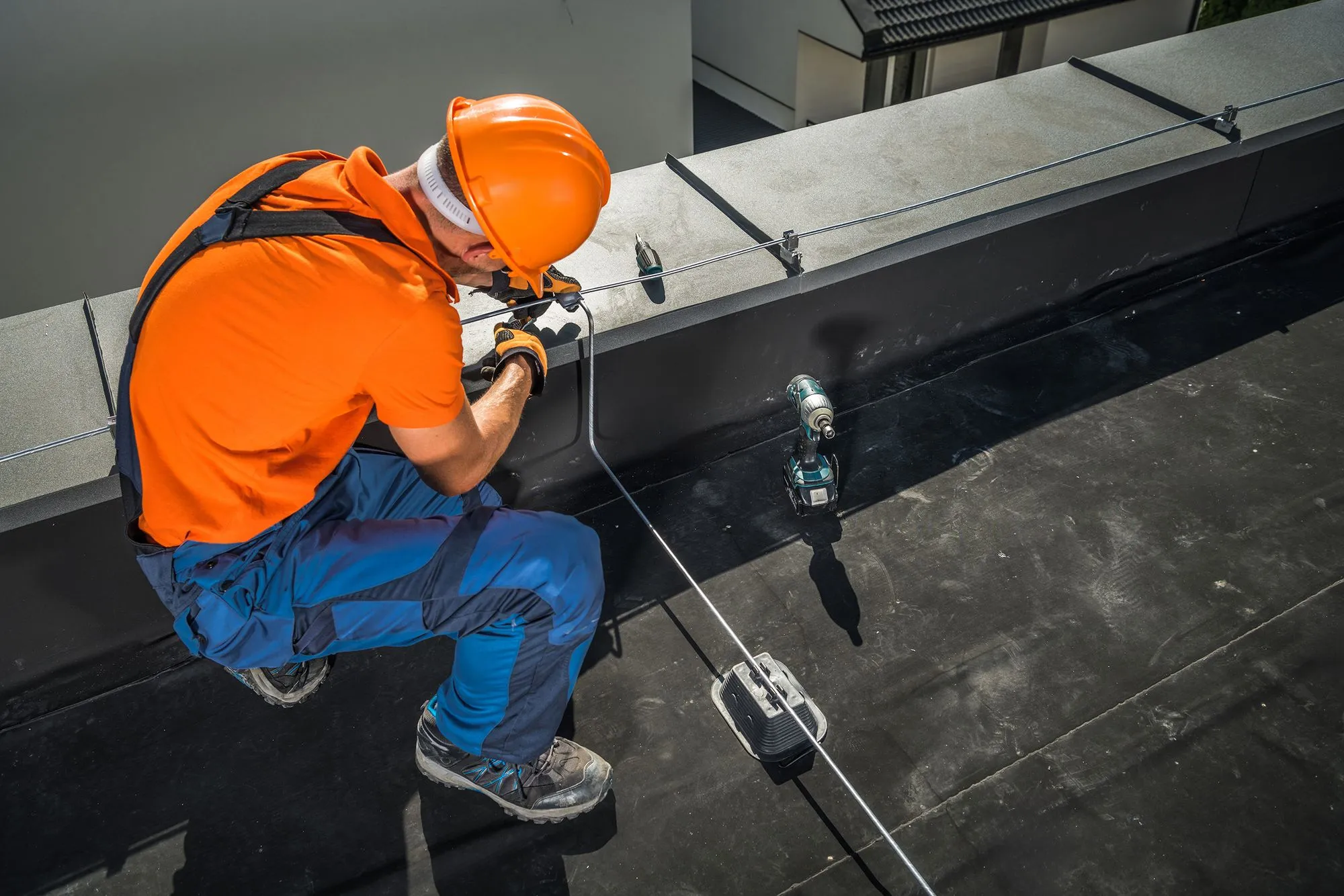 Technieker plaatst een aluminium geleider op een plat dak als onderdeel van een bliksembeveiligingssysteem