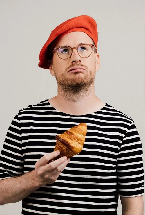 Portrait of Paul Taylor with a beret and a croissant