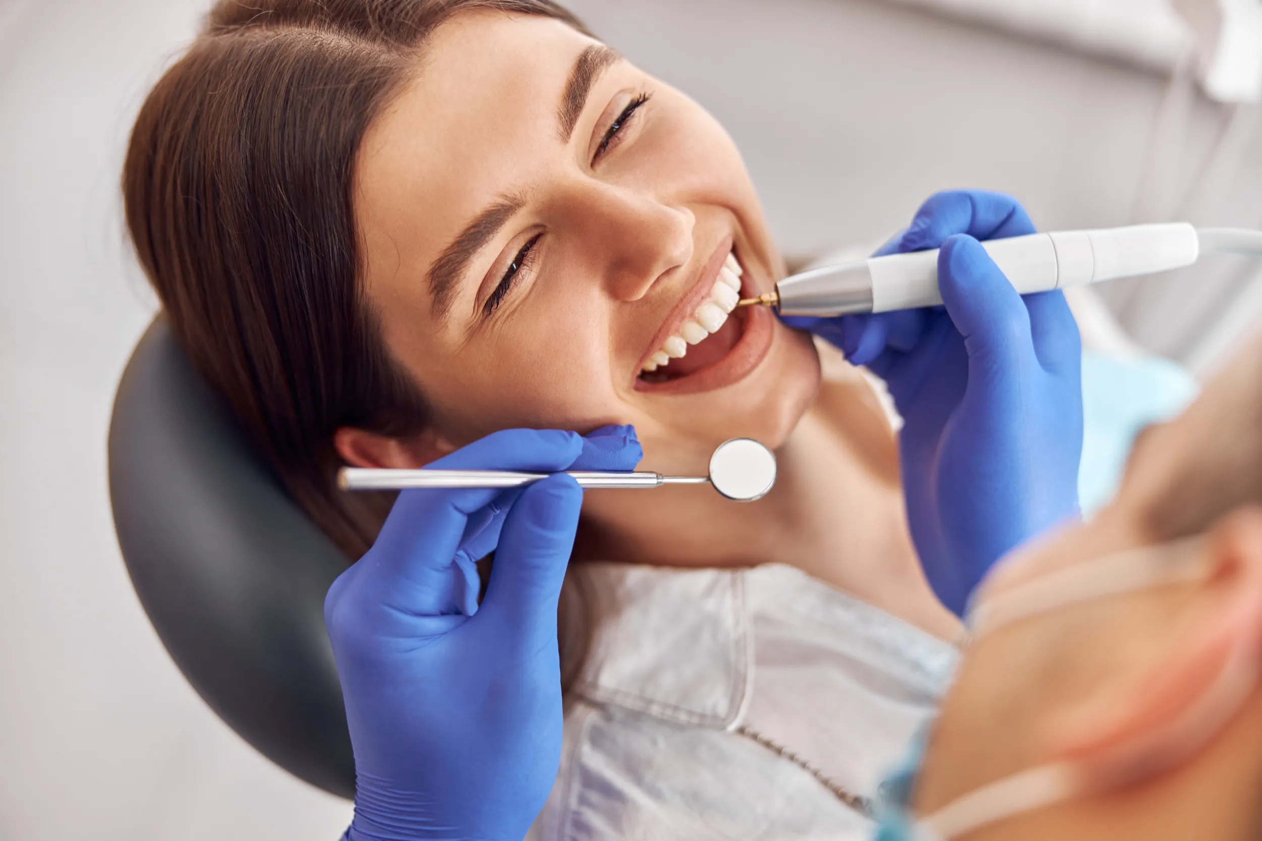 Patient smiling during dental checkup with dentist using dental tools